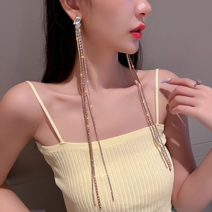 Close-up of long gold tassel earrings with shimmering crystals on a female model