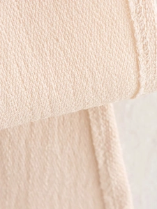 Close-up of cream knit fabric with a detailed waffle texture and high-quality stitching