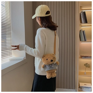 Detail shot of a plush teddy bear crossbody bag wearing a grey hoodie on a brown strap