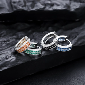 Gros plan de boucles d'oreilles créoles argentées pavées de zircons orange vert noir et bleu