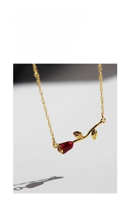 Close-up of red enamel rose pendant with golden petals and twisted chain detail