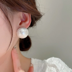 Close-up of elegant silver ball stud earring with unique wrinkled texture on a model