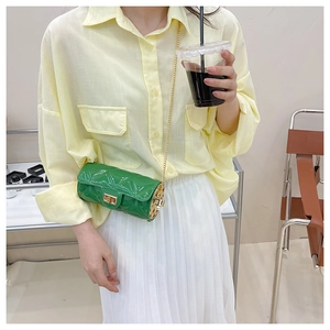 Close-up of green cylinder jelly bag featuring gold metal chain and side镂空 detail