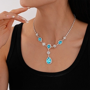 Close-up of vintage teardrop blue crystal necklace with diamond halo on neck
