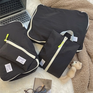 Detailed set of black travel organizers with white zippers and neon yellow pulls on soft rug