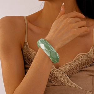 Detail of green acrylic geometric faceted bangle with marble texture on model wrist