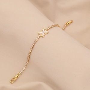 Elegante bracciale in oro con zirconi e ciondolo a stella in madreperla su sfondo beige