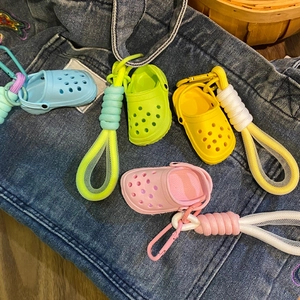 Detail of four colorful mini clog shoe keychains with matching woven straps on denim