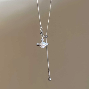 Détail du pendentif planète Saturne argenté avec perle et croix sur une chaîne fine