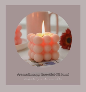 Detailed view of a burning pink Rubik's cube bubble candle in a cozy home setting