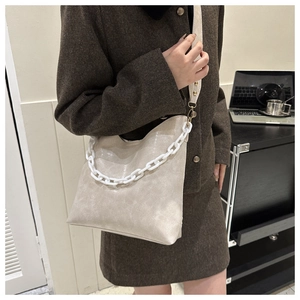 Chic beige hobo crossbody bag with chunky white chain and wide textile strap on model
