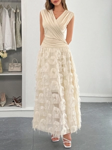 Détail du haut cache-cœur col en V et de la jupe à franges beige sur une robe longue
