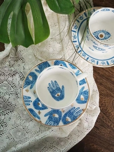 Nordic ceramic coffee cup set with blue evil eye pattern and gold trim on wooden table