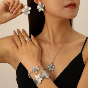 Detailed close-up of a silver floral jewelry set with textured petals on female model
