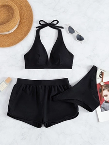 Detailed flat lay of a black three-piece halter swimsuit with boyshorts and beach accessories