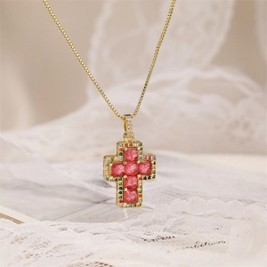 Macro detail of gold cross pendant necklace featuring pink center stone and colorful zircons
