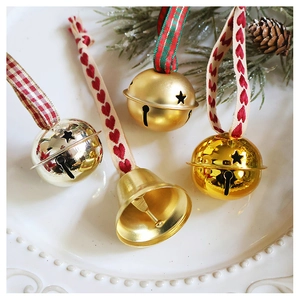 Detailed close-up of metallic Christmas bells with star cutouts and festive ribbon ties