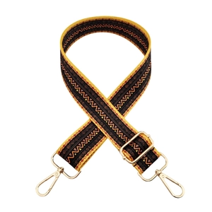 Detailed view of yellow and black ethnic pattern bag strap with gold metal buckles