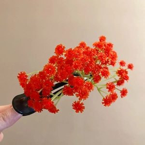 Close-up of red acrylic floral hair clip with green stems and elegant black hair pin