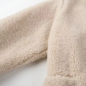 Detailed close-up of beige faux shearling coat cuff showing thick plush texture