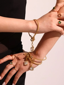 Close-up of gold twisted bracelets with crystal charms and multicolored gemstone rings