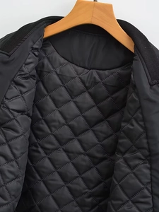 Detailaufnahme des schwarzen Steppfutters der Jacke mit Rippstrickkragen auf Holzbügel
