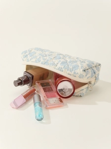 Quilted cotton makeup bag with blue floral pattern and cosmetics on cream background
