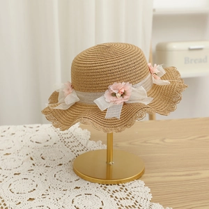 Détail du chapeau de paille avec fleurs roses et nœud en dentelle sur support