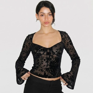 Détail du haut en tulle noir avec motifs floraux floqués et manches évasées rétro