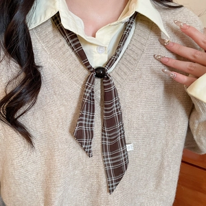 Detail of dark brown plaid chiffon scarf necklace with a round black clasp on model