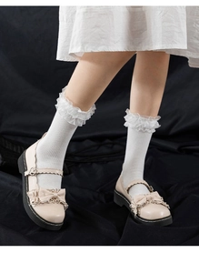 Detail of beige Mary Jane shoes with bow decoration and white ruffle edge ankle socks