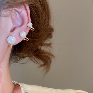 Detailed view of elegant gold clip-on earrings with varying sizes of white pearls