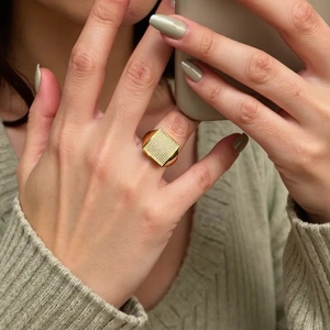 Macro detail of a 18K gold-plated square pavé ring showing crystal settings and polish