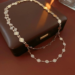 Detail of vintage gold clover necklace with hollow diamond patterns on brown leather case