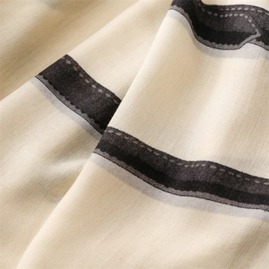 Close-up of beige cotton-linen scarf fabric with black and grey chain belt patterns