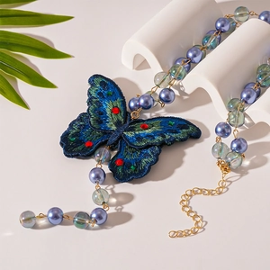 Vintage embroidered butterfly necklace with blue pearls and glass beads on a stand