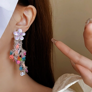 Vue macro de boucles d'oreilles pendantes perlées avec fleurs et sequins smiley