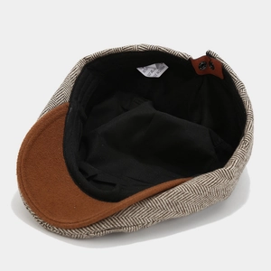 Detail view of adjustable leather strap and inner lining on herringbone newsboy cap