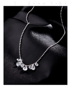 Detail of s925 silver necklace with teardrop crystals on a textured black leather background