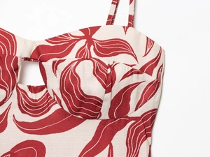 Close-up of red leaf print on cream midi dress featuring pleated fabric details