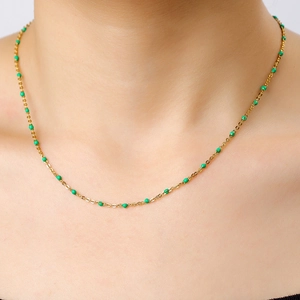 Close-up of gold stainless steel chain necklace with green enamel beads on a model