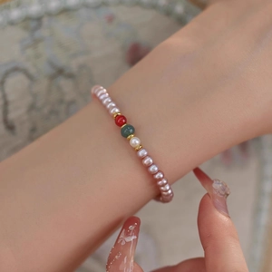 Detail of freshwater pearl and agate beaded bracelet on a wrist with soft lighting