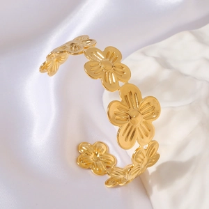 Detail of gold floral open bangle featuring 3D five-petal flowers and metallic shine