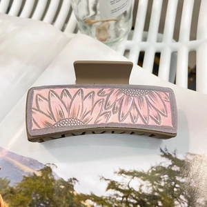 Detailed view of a brown matte hair claw clip featuring pink and grey sunflower patterns