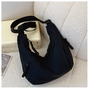 Dettaglio ravvicinato di una borsa a tracolla in nylon nero a mezzaluna con zip e texture