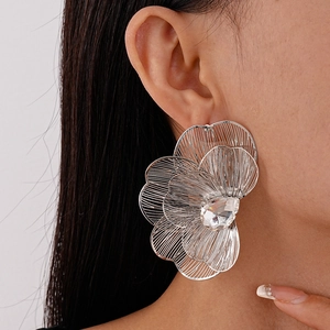 Close-up of a silver mesh flower earring with a crystal center on a model's ear