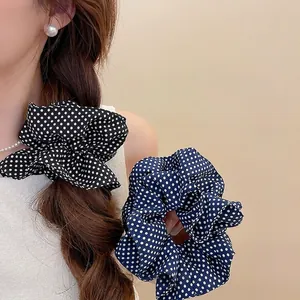 Elegant polka dot fabric scrunchies for ponytails shown on hair and held in hand