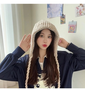 Détail d'un bonnet en grosse maille beige avec de longues lanières tressées