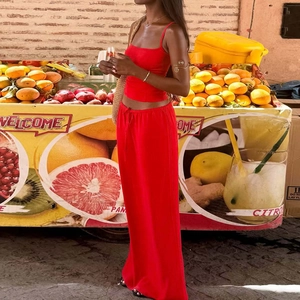 Detail of red two-piece set featuring thin strap crop top and high-waisted wide-leg pants