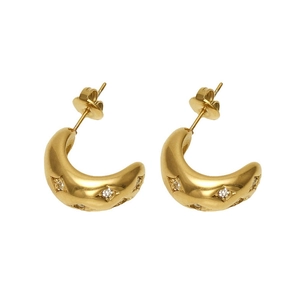 Détails macro des boucles d'oreilles créoles dorées en C avec strass scintillants